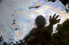 Cancer victim Maria Garofalo reflected in the stream behind her home in the Ecuadorean Amazon.