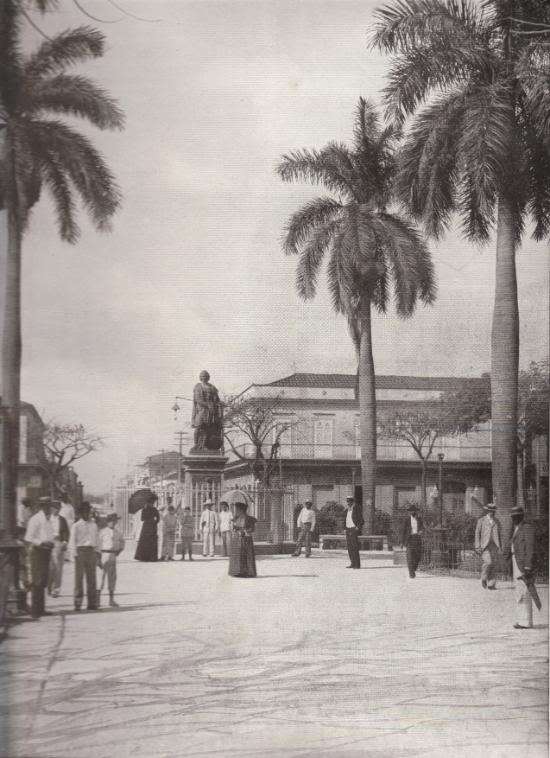 PLAZA AND COLUMBUS MONUMENT, CARDENAS, CUBA: This monument was erected in 1862, by order of Isabella II of Spain, and presented to the City of Cardenas. It is one of the many costly works of art that Spain has left in the Islands as a compensation for her misrule and extortion. The stately date palms on either side form an appropriate frame for a strikingly beautiful picture.