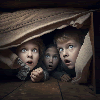 Frightened children hiding under the bed